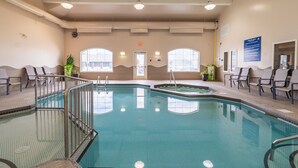 An indoor swimming pool with a tiled floor, metal railings, and chairs around the perimeter. - Days Inn & Suites by Wyndham Brandon (Brandon)