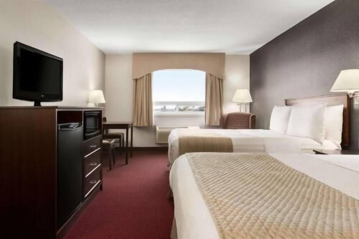 Une chambre d’hôtel avec un lit, un bureau, une télévision et une vue sur la ville.