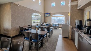 A hotel dining area with tables, chairs, a coffee station, and large windows. - Days Inn & Suites by Wyndham Brandon (Brandon)