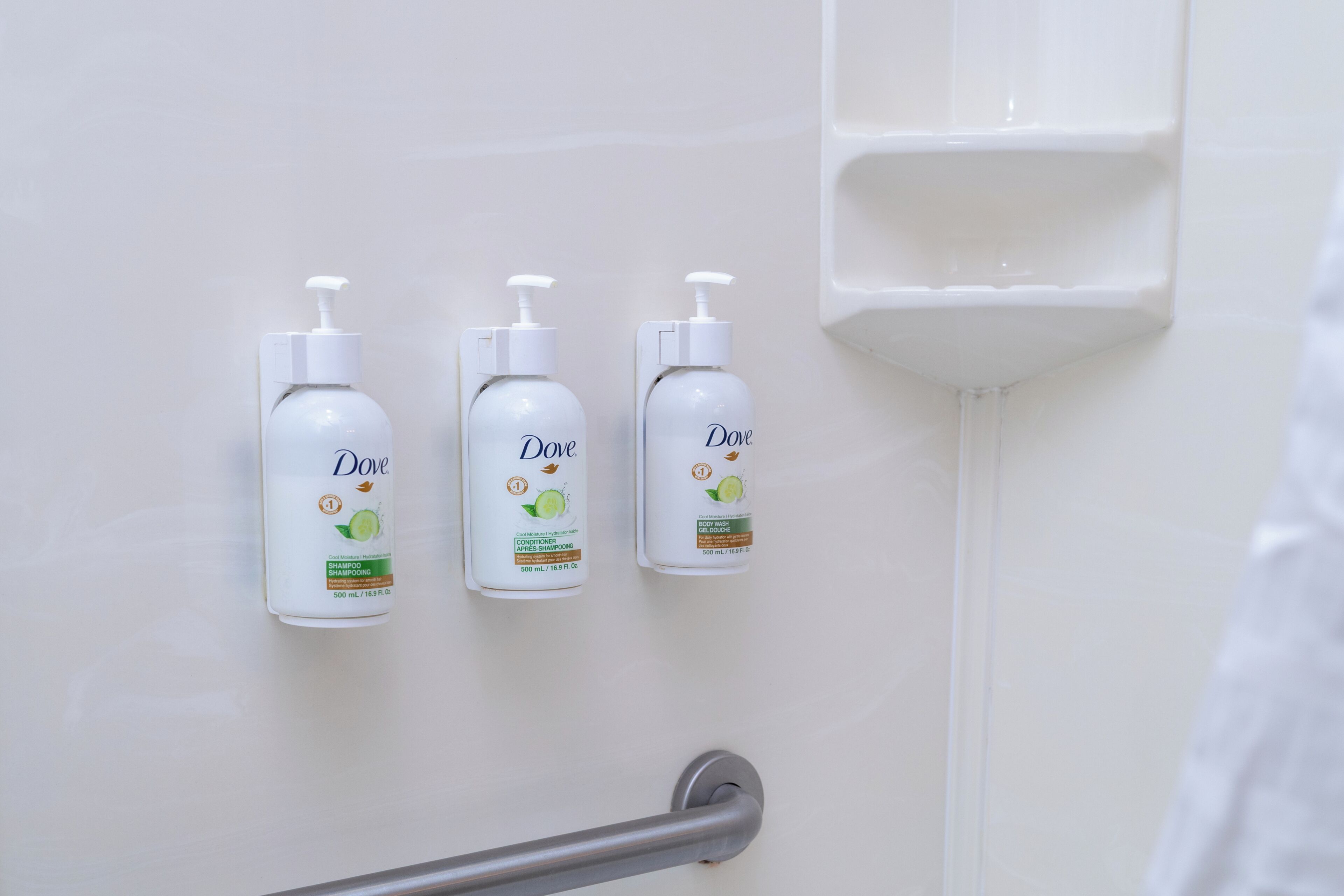 Tre flaconi di shampoo Dove montati su una parete.