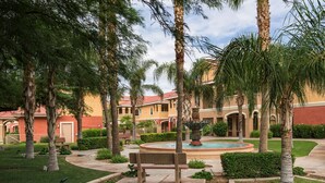 A courtyard with palm trees, a fountain, and a bench. - Westgate Painted Mountain Golf Resort (Mesa)