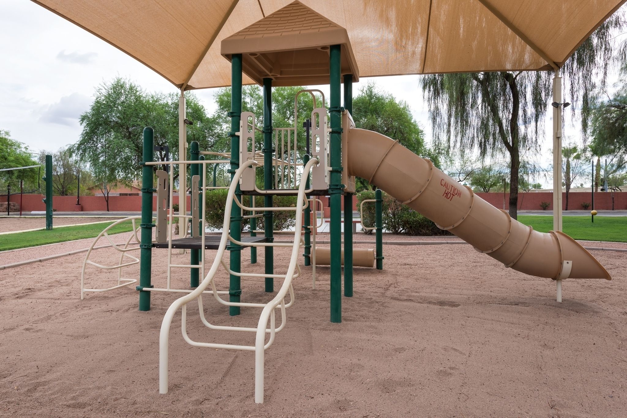 Ein Spielplatz mit Rutsche und Klettergerüsten, beschattet durch eine Markise.