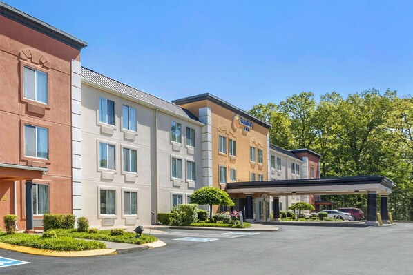 A hotel with multiple buildings, a covered parking area, and a well-maintained garden.