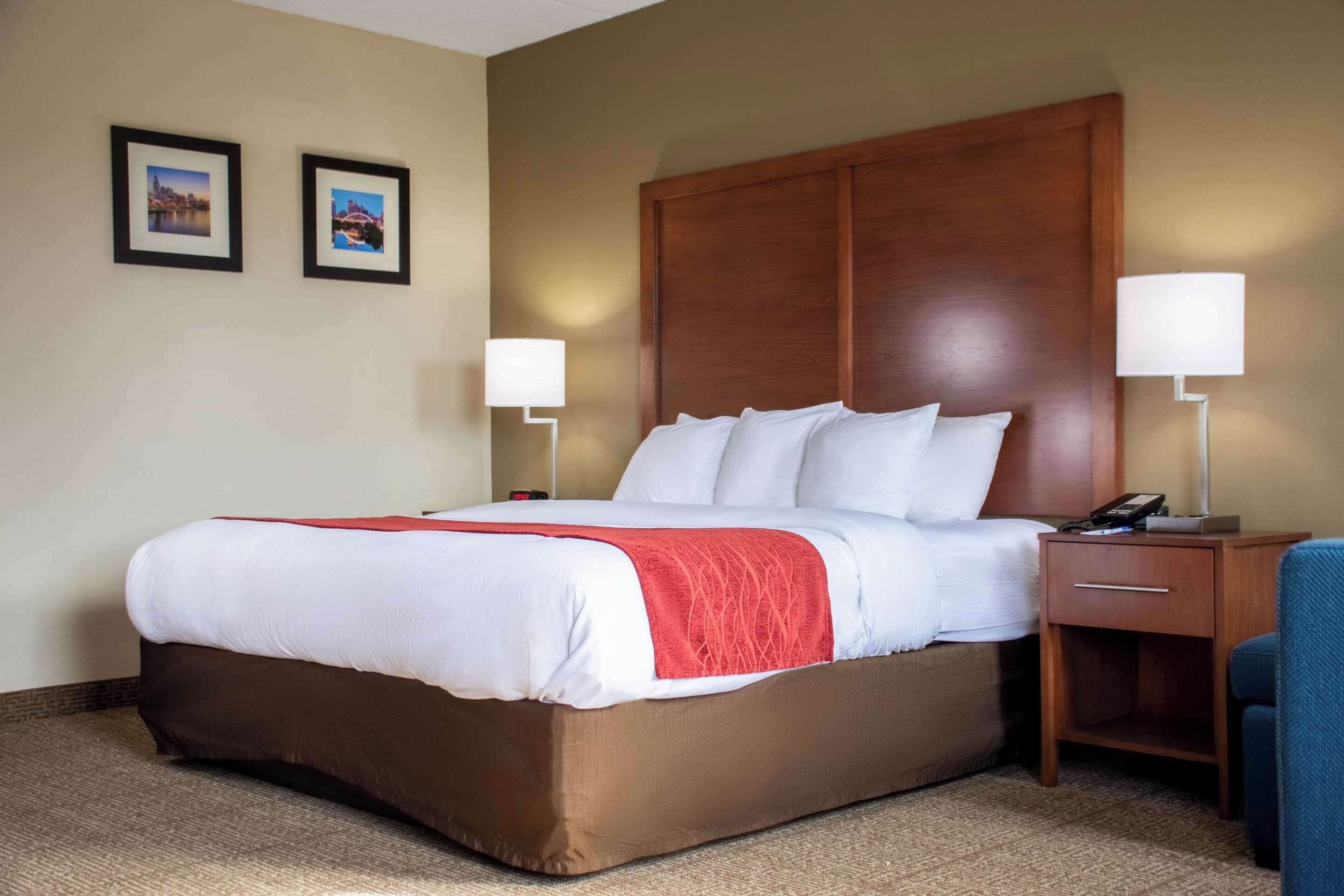 A hotel room with a large bed, two bedside tables with lamps, and two framed pictures on the wall.