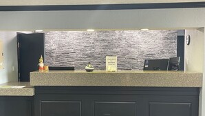 En reception med væg i stengulv, et skilt der tilbyder hjælp og en betalingsterminal.