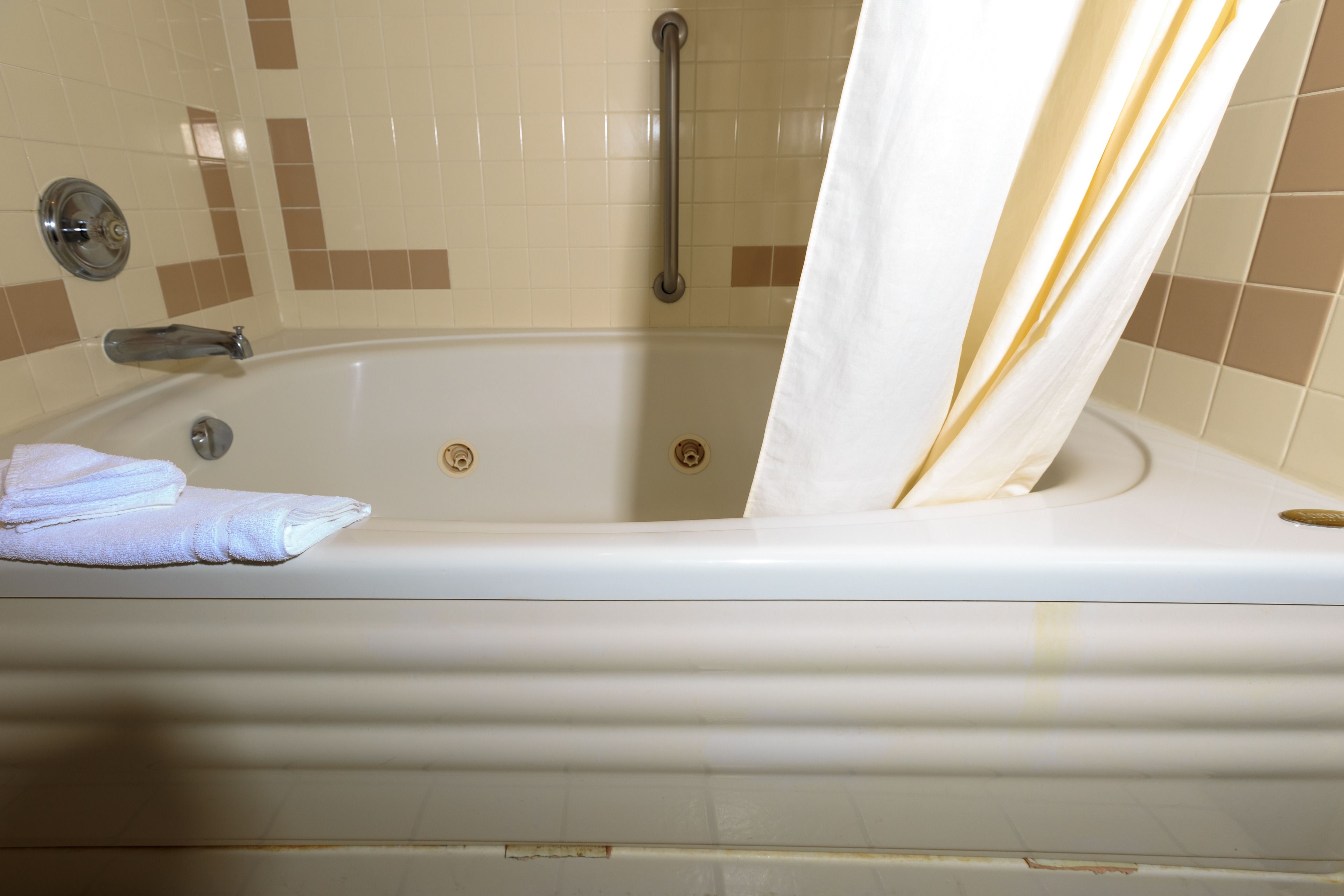 Una bañera con cortina de ducha, una toalla y un asidero.