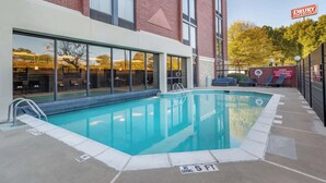 A swimming pool adjacent to a building with large windows and a brick facade. - Drury Inn & Suites Atlanta Airport (Atlanta)