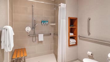 Un baño moderno con ducha, inodoro y un pequeño banco de madera.