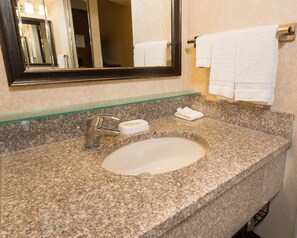A granite bathroom sink with a mirror above it, a towel rack with two white towels, and a soap dish. - Drury Inn & Suites Atlanta Airport (Atlanta)