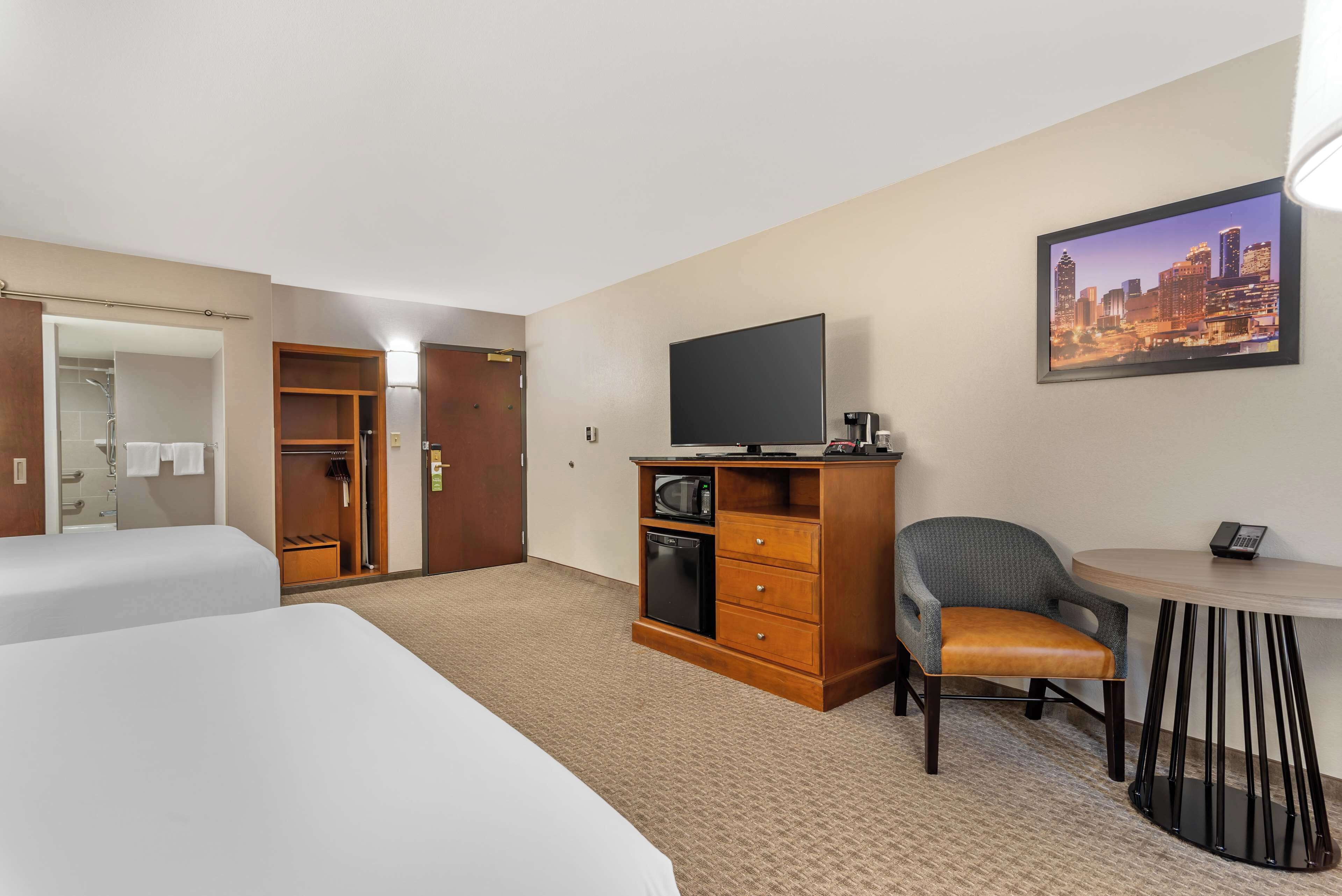 A hotel room with two beds, a TV, a desk with a chair, a microwave, and a coffee maker.