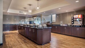 A modern kitchen with a central island, dark wooden cabinets, and a Coca-Cola vending machine. - Drury Inn & Suites Atlanta Airport (Atlanta)