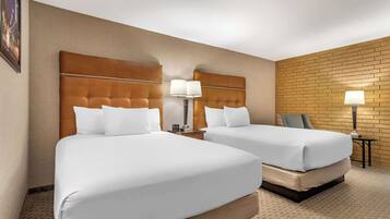 Ein Hotelzimmer mit zwei Betten, einer Wand mit Ziegelmuster und einem kleinen Tisch mit einer Lampe.