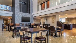 A spacious indoor area with multiple tables and chairs, a kitchen area, and a staircase leading to an upper level. - Drury Inn & Suites Atlanta Airport (Atlanta)