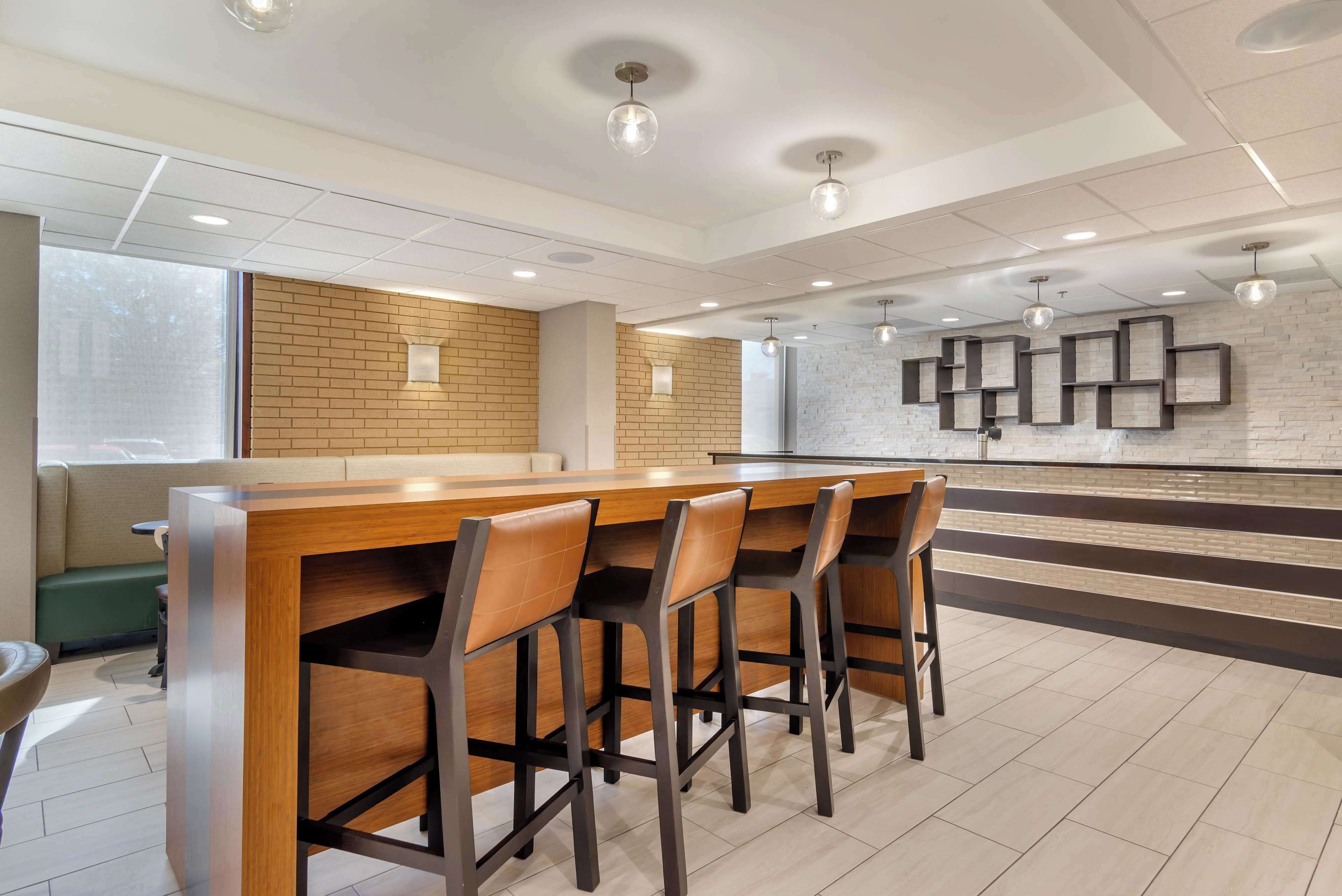 A modern bar area with a wooden counter and four bar stools.