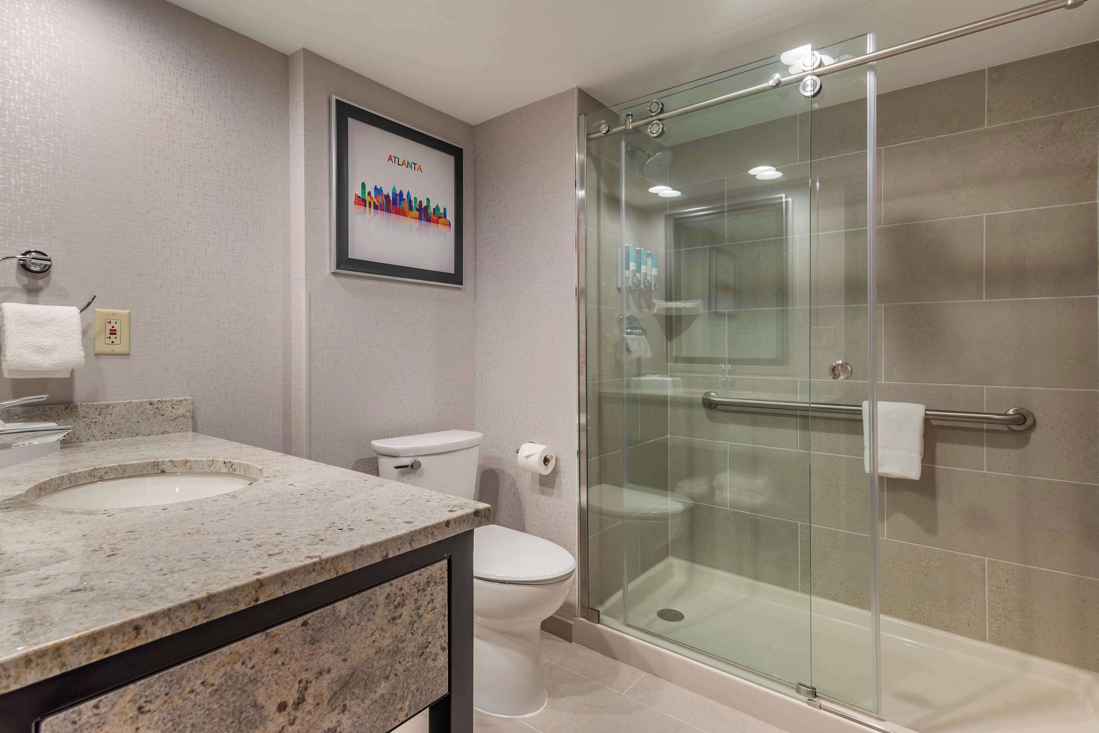 A modern bathroom with a glass-enclosed shower, a double sink vanity, and a toilet.