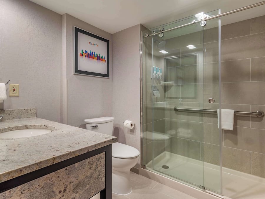 A modern bathroom with a glass-enclosed shower, a double sink vanity, and a toilet.