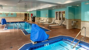 A swimming pool area with multiple lanes, lounge chairs, and a covered seating area. - SpringHill Suites Anchorage Midtown (Anchorage)