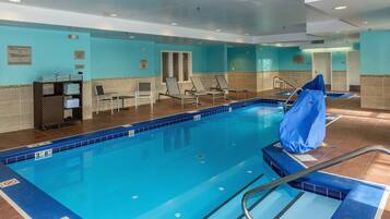 Una piscina con una profundidad de 9 metros, sillas de descanso y un perchero para toallas.