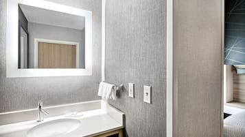 A modern bathroom with a large mirror, a white sink, and a towel rack.