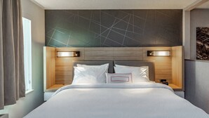 A modern hotel room with a large bed, two bedside tables, and a geometric-patterned headboard. - SpringHill Suites Anchorage Midtown (Anchorage)