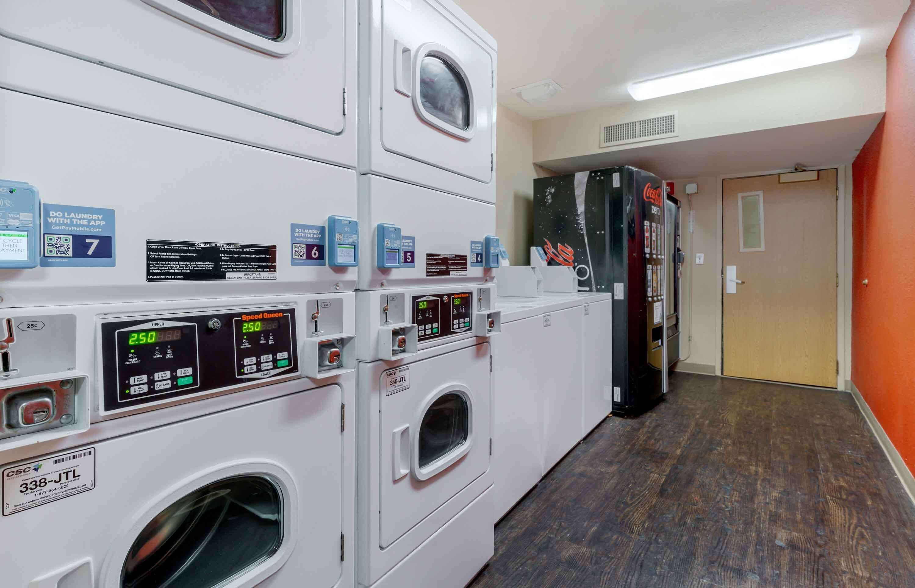 A laundry facility with multiple washing machines and dryers, each labeled with a number and instructions.