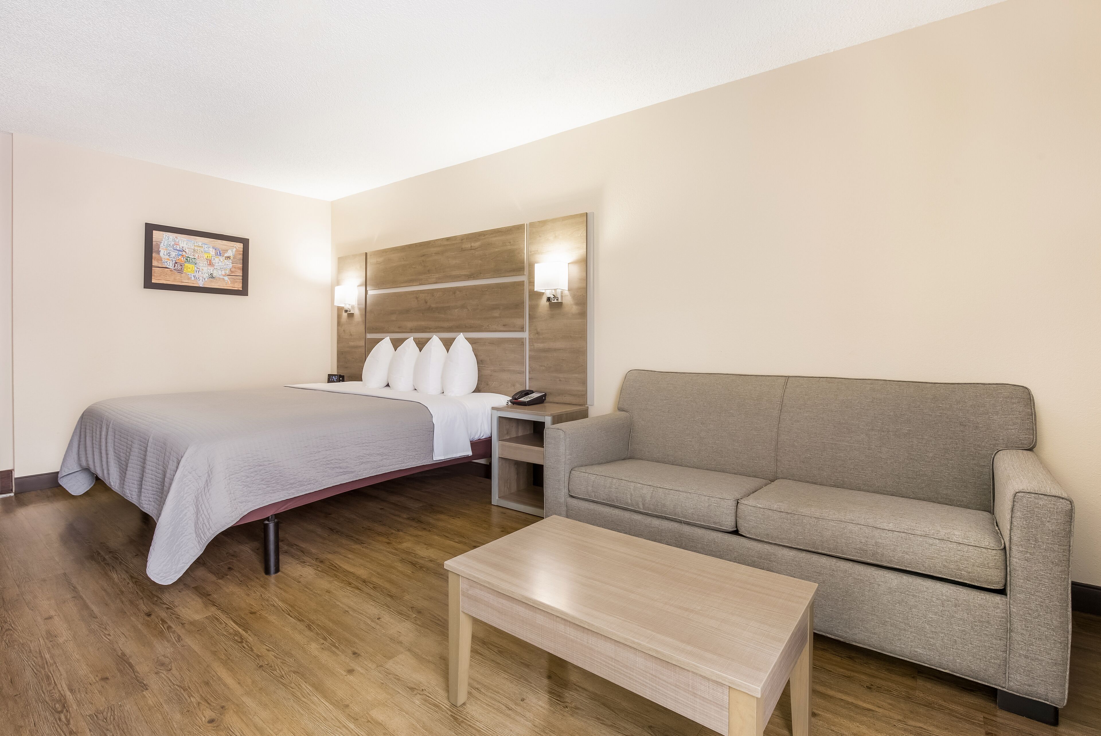 Ein Hotelzimmer mit Bett, Sofa, Couchtisch, Nachttisch und einer Wandlampe.