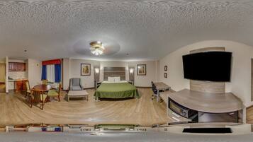 A hotel room with a bed, a desk, a chair, a TV, and a fireplace.