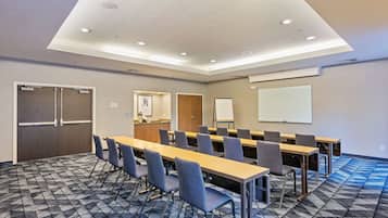 Una sala conferenze con un lungo tavolo, sedie, una lavagna e uno schermo per proiettore.
