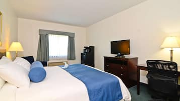 A hotel room with a bed, a desk, a chair, a television, and a window with curtains.