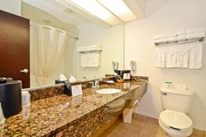 A bathroom with a granite countertop, white sink, and toilet. There are towels hanging on the wall and a mirror above the sink. - Best Western Gas City (Gas City)