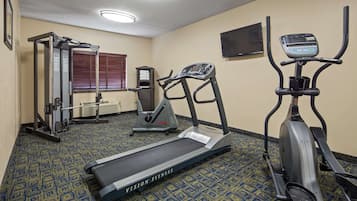 Sala de ginástica com esteira, elíptico e máquina de pesos.