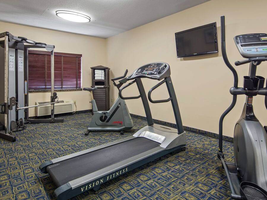 Un gimnasio con cinta de correr, elíptica y máquina de pesas.