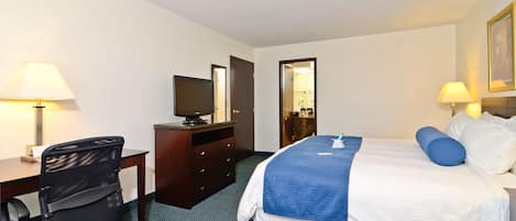 A hotel room with a bed, desk, chair, television, and lamps.