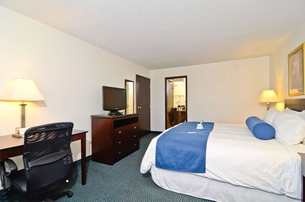 A hotel room with a bed, desk, chair, television, and lamps.