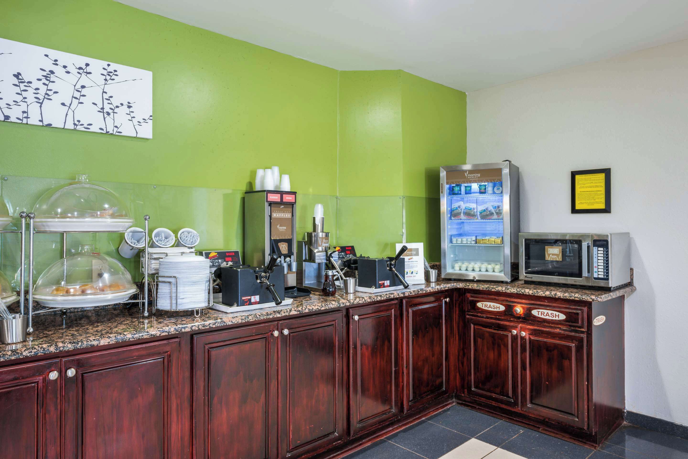 A kitchen area with a coffee machine, a microwave, and a trash bin.