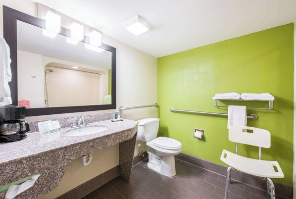 A bathroom with a granite countertop sink, a white toilet, a green wall, and a white shower chair. - Sleep Inn Statesville I-40 (Statesville)
