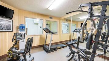 A gym with exercise equipment, a water dispenser, and a television on the wall.