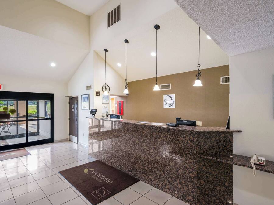 A hotel reception area with a granite counter, a reception desk, and a sign for the Sleep Inn.
