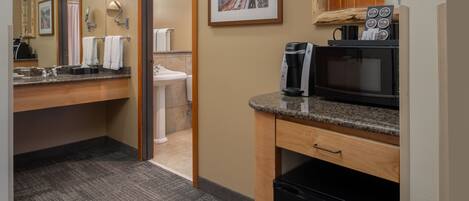 A hotel bathroom with a sink, mirror, towel rack, and a framed picture on the wall.