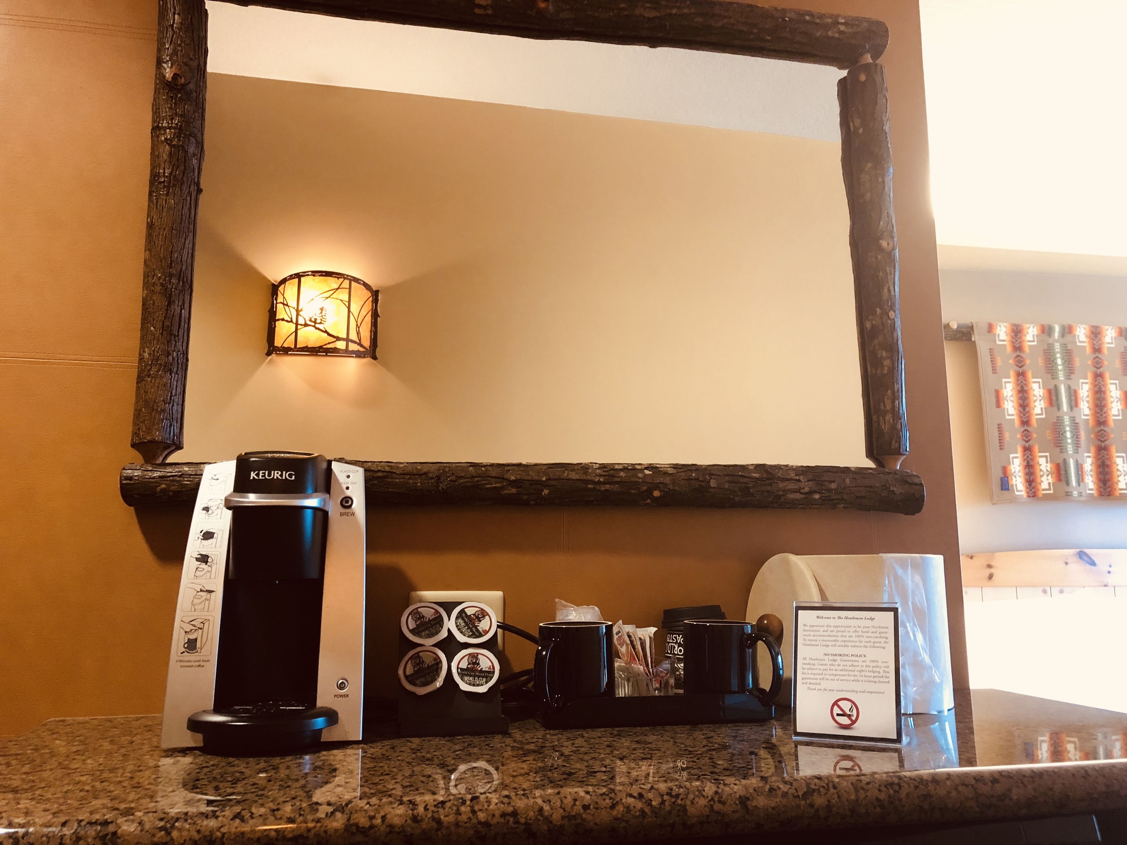 Een koffiehoek met een Keurig machine, mokken en een bord.