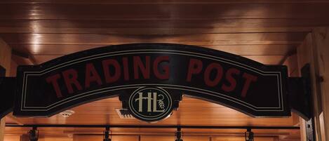 Interior de madera con un letrero que dice "TRADING POST" y un logo con "HL".