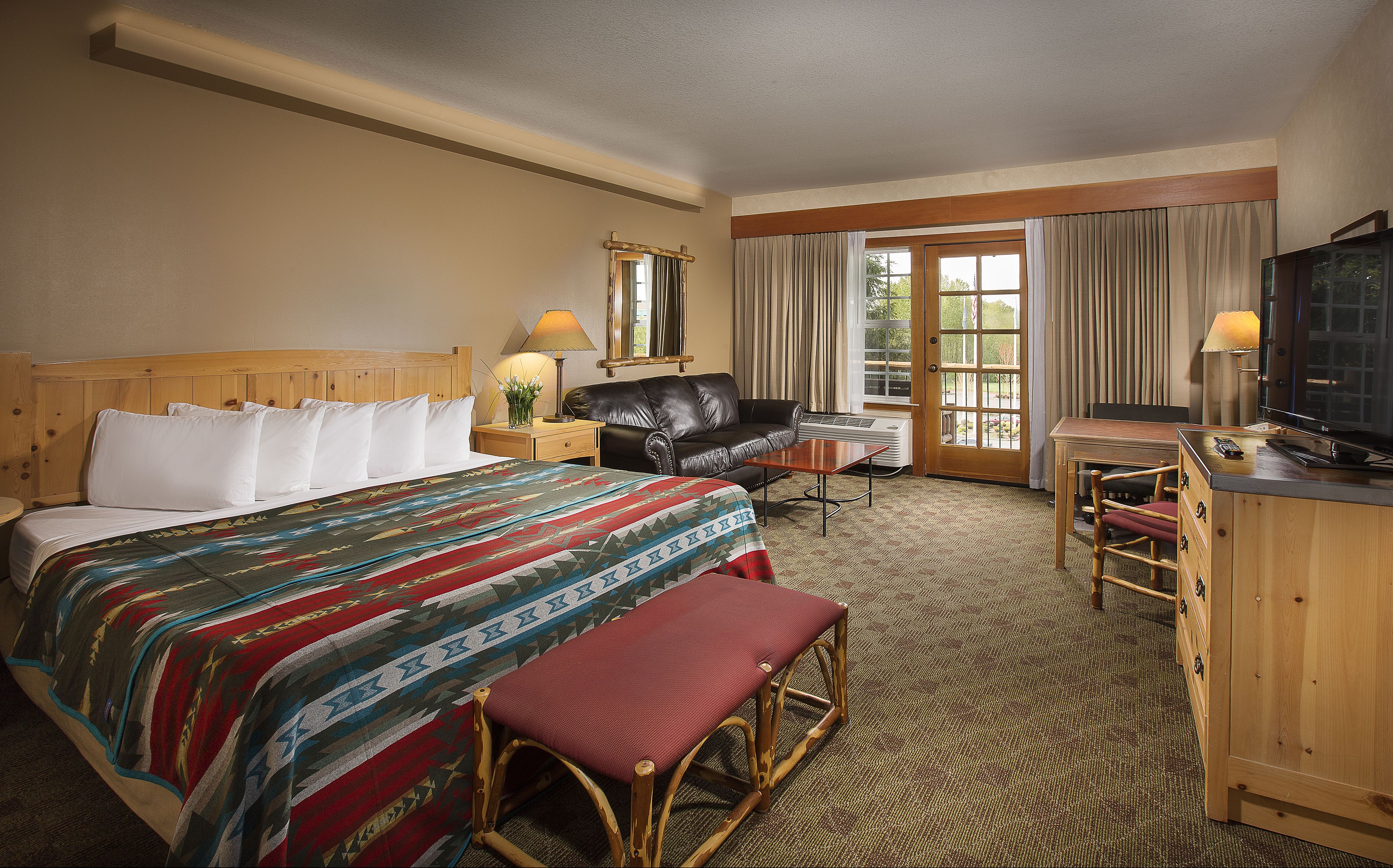 A hotel room with a bed, a desk, a chair, a television, and a window with curtains.