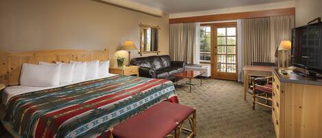 A hotel room with a bed, a desk, a chair, a television, and a window with curtains.
