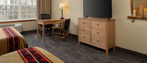 A hotel room with a bed, a desk, a chair, a TV, and a dresser.