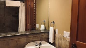 A bathroom with a sink, toilet, and shower area.