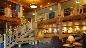 Interior de madeira com escadaria, área de estar e balcão de recepção.