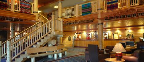 A wooden interior with a staircase, seating area, and a reception desk.