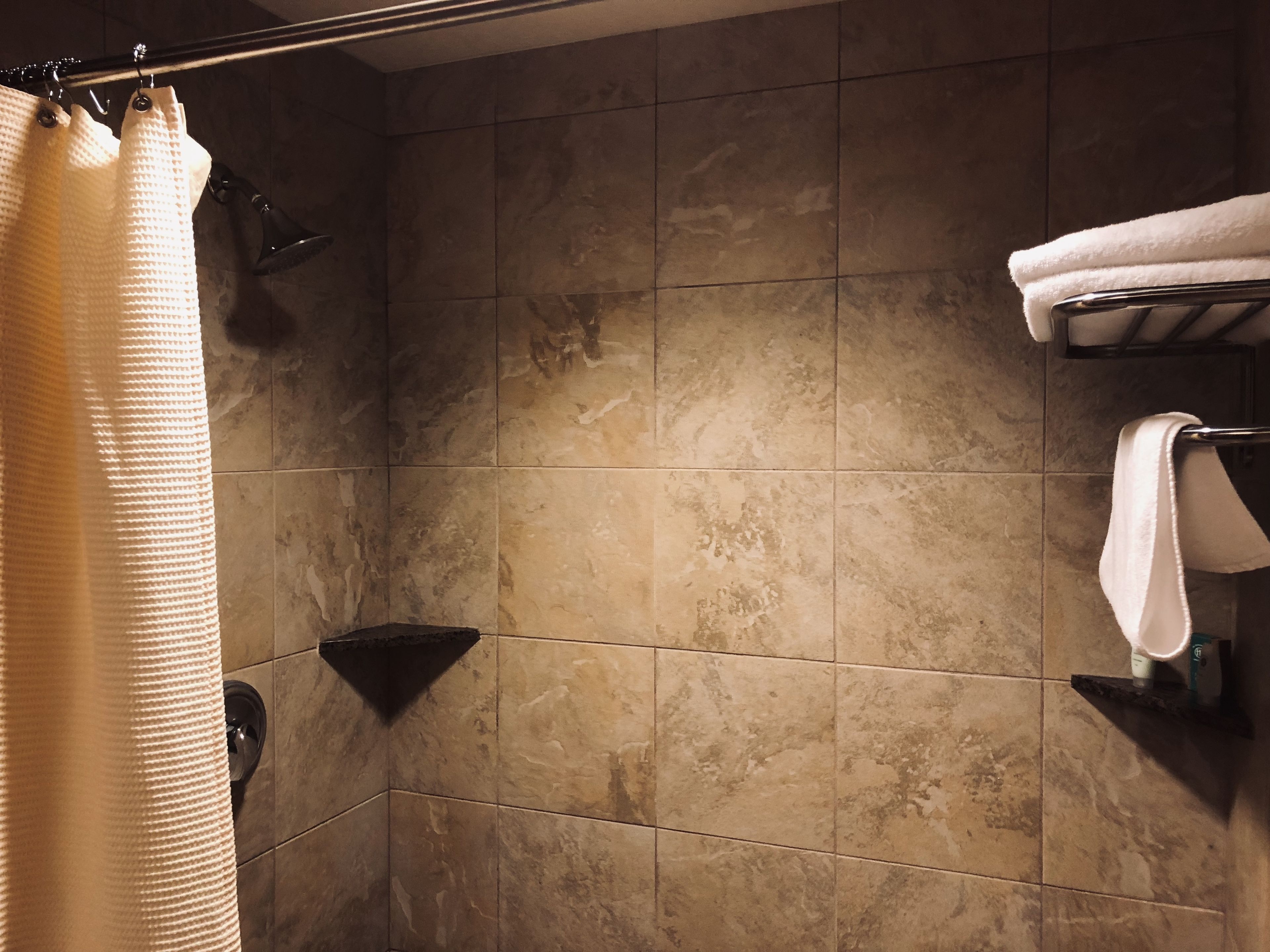 Un baño con cortina de ducha, toallero y ducha.