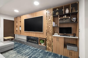 Uma sala de estar moderna com televisão de tela plana, estantes embutidas, lareira e mesa de centro.