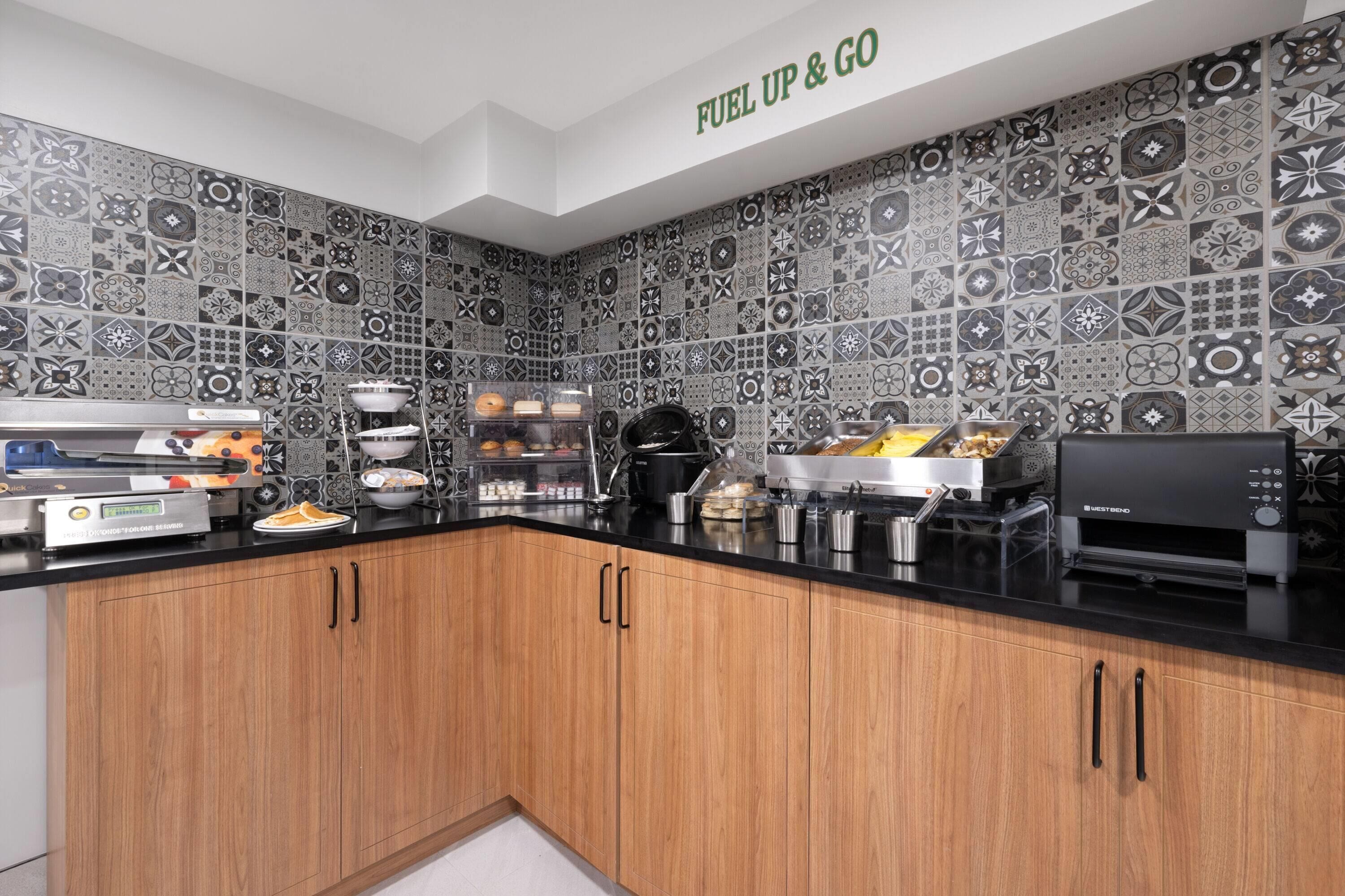 A kitchen with a black countertop, wooden cabinets, and a backsplash with various patterns.